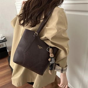 Minimalist dark brown tote bag with leather texture and cute rabbit charm accessory