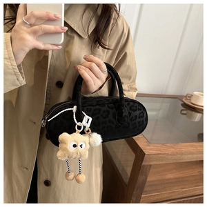 Detail of dark leopard print pillow bag with creative plush cartoon charm accessory