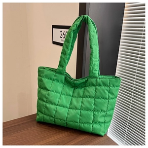 Detailed close-up of green quilted nylon tote bag with square stitching and long shoulder straps