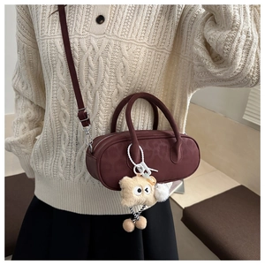 Detail of burgundy leopard embossed mini cylinder bag with cute plush bear charm