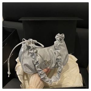 Close-up of a light blue satin shoulder bag with ruffles and a silver butterfly charm