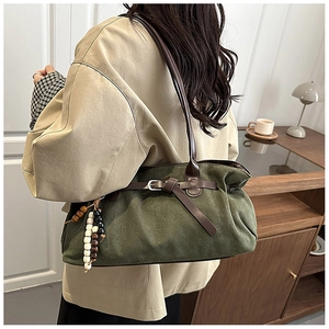 Detail of dark green vintage tote bag featuring brown leather straps and beaded charms