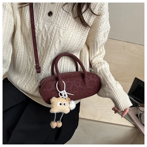 Detail of burgundy leopard print pillow bag with fluffy monster charm on red crossbody bag