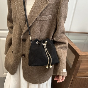 Retro black matte bucket bag with gold chain and pearl accents on a stylish model