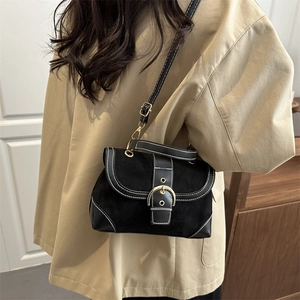 Vintage black crossbody bag with contrast stitching and large gold buckle in a soft interior setting