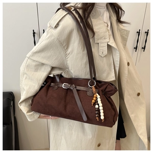 Detail of dark brown suede tote bag with ethnic wood bead charm and buckle accent