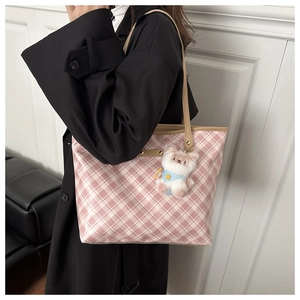 Detail of pink plaid tote bag featuring leather trim and a cute plush bear charm accessory