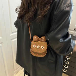 Brown mini crossbody bag with crochet flowers and leather bow on a model outfit