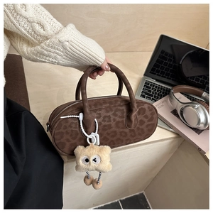 Close-up of leopard print pillow bag with plush charm on a cozy workspace desk