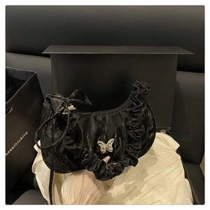 Detail of black pleated half-moon bag with silver butterfly charm and ruffled trim