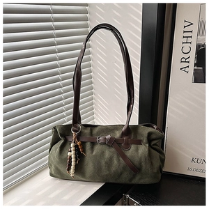 Detail of olive green suede tote bag with brown leather handles and wooden bead charm