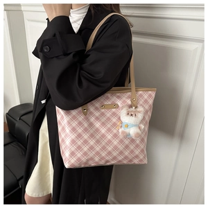 Pink checkered tote bag detail with plush bear charm and brown leather shoulder straps