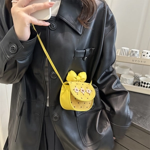 Mini yellow crossbody bag with white flower and bow detail, worn with a black leather jacket