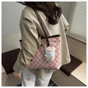 Detail of pink plaid tote bag with brown leather handles and cute plush bear charm