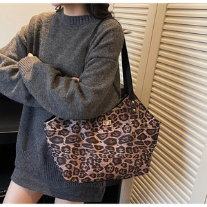 Detail of leopard print tote bag with golden twist lock and slim black leather straps