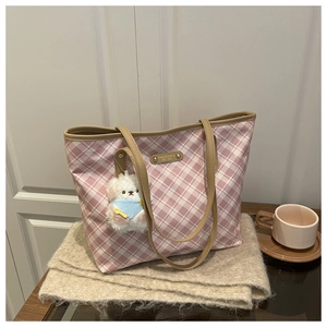 Detail of pink plaid tote bag with brown leather straps and a plush puppy charm