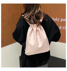Detail of light pink nylon drawstring backpack with soft texture and ribbon straps