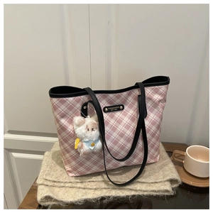 Detail of pink plaid tote bag with plush bear charm and metallic logo on soft scarf
