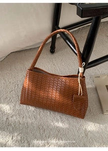 Détail du sac sous le bras en cuir tressé marron avec breloques décoratives