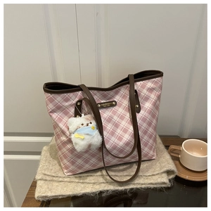 Detail of pink plaid tote bag with brown leather strap and cute white bear keychain