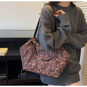 Detail of large leopard print tote bag with black shoulder straps and metal twist lock