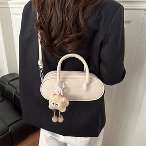 Chic beige pillow crossbody bag with cute plush bear charm on a stylish female model
