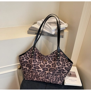 Detail of leopard print tote bag with black leather straps and gold metal twist lock