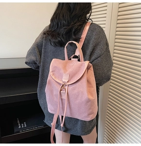 Close-up of a pink matte leather backpack with flap design and metal buckle on a model