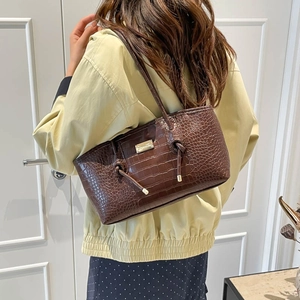 Brown crocodile embossed leather tote bag with gold logo on a shoulder strap model