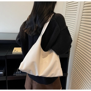 Close-up of a white minimalist hobo shoulder bag with textured leather and stitching detail