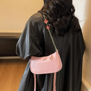 Sac bandoulière rose en similicuir avec chaîne fraise et logo embossé en mode lifestyle