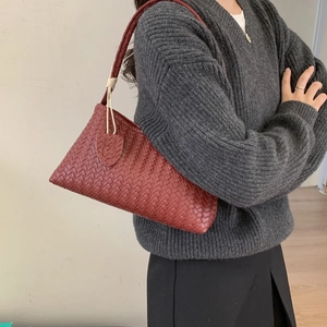 Sac à épaule minimaliste en cuir tressé rouge foncé avec détail de nœud sur la bandoulière