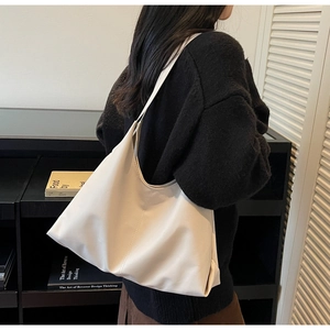 Side view of white leather hobo tote bag showing wide strap and vertical seam detail