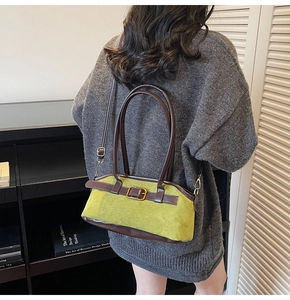 Close-up of green suede shoulder bag with brown leather trim and vintage metal buckle