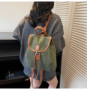 Detail view of olive green canvas backpack with brown leather trim and drawstring closure