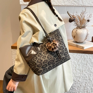 Fashionable leopard print tote bag with brown leather handles and plush heart charm