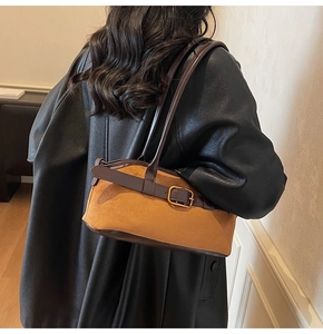 Detailed view of vintage brown suede shoulder bag texture and metallic buckle hardware