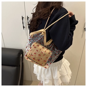 Detail of transparent PVC tote bag featuring cherry patterns and a brown inner pouch