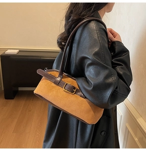 Close-up of brown suede shoulder bag texture with golden buckle on a black leather coat