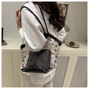 Detail of transparent PVC cherry tote bag with black inner pouch on shoulder