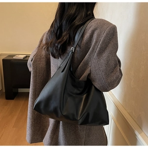 Minimalist black oversized shoulder bag with slouchy texture on a model in grey blazer