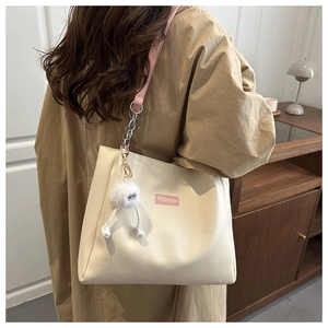 Detail of off-white leather bucket bag with pink FASHION label and furry monster charm