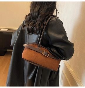 Detail of vintage brown suede crossbody bag with leather strap and gold buckle