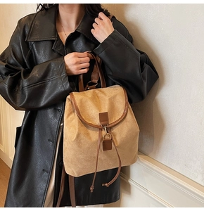 Detail of khaki suede backpack with brown leather trim and metallic lock closure