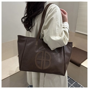 Detailed texture of dark brown pebbled leather tote bag with embossed circular logo