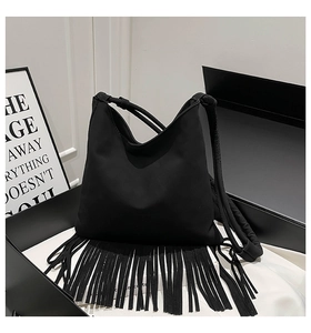 Détail du sac hobo noir à longues franges, présenté sur une surface douce et minimaliste