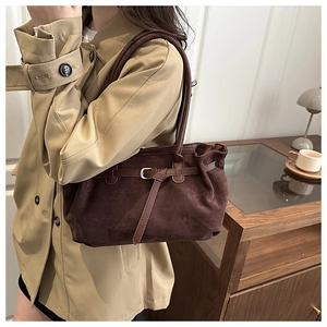 Detail of dark brown suede tote bag featuring metallic buckle straps and premium texture