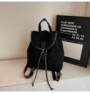 Detail view of black corduroy backpack featuring gold metal clasp and tassel drawstring