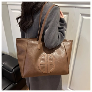 Detail shot of vintage brown tote bag featuring embossed AB logo and matte texture