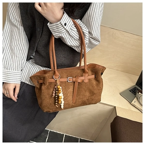 Detailed texture of brown suede tote bag featuring silver buckle and wooden bead tassel